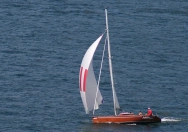 Ein Holuboot mit individiuell gestaltetem Gennaker in rot und weiß beim Segeln